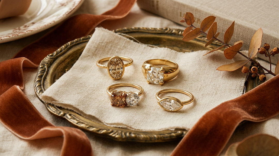 Fall 2026 engagement ring editorial flat lay with champagne diamond, old mine cushion, toi et moi, and marquise rings on antique brass tray with velvet ribbon and autumn foliage